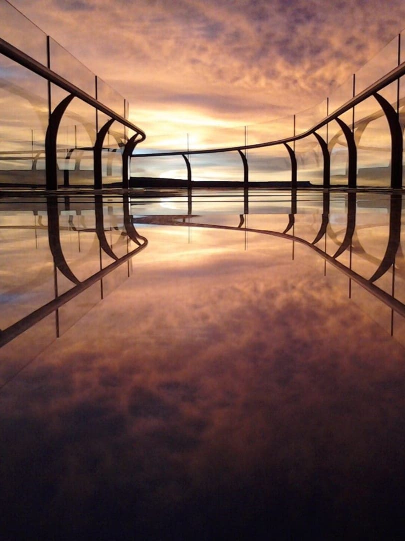 A view of the sky and water from inside an arch.